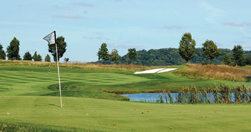 scenic putting green with flag overlooking pond and fountain at Jericho National Golf Club