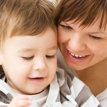 young mom looking down at book while reading with her toddler son