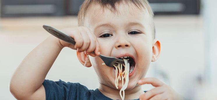 young boy eating spaghetti