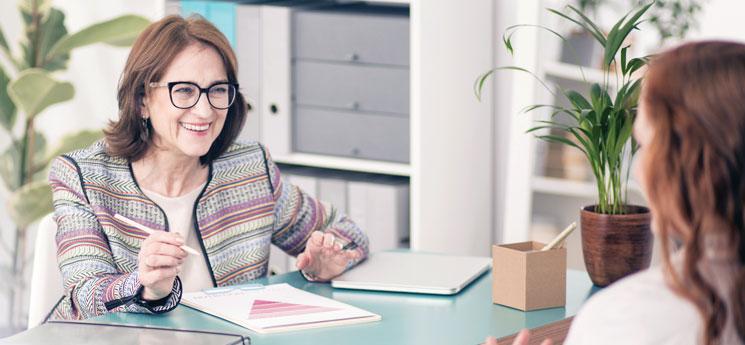 Nurse Navigator sitting at desk speaking with young female client