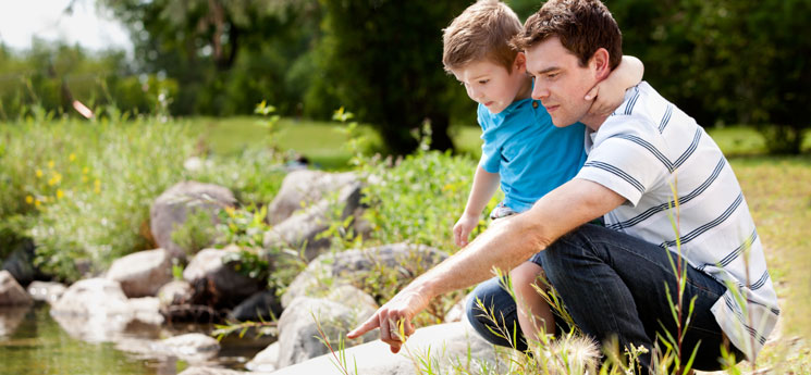 father with young boy outdoors by a stream